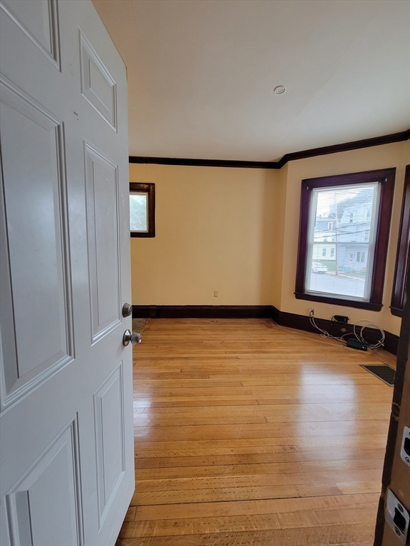 a view of an empty room with wooden floor and a window