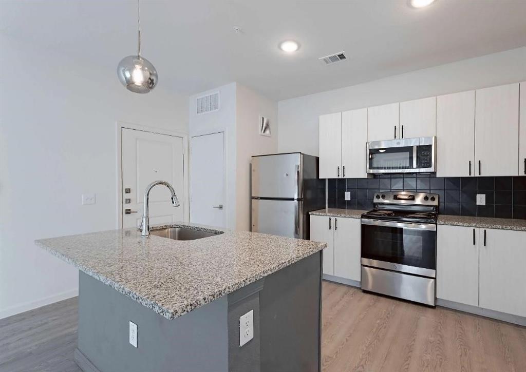 a kitchen with stainless steel appliances granite countertop a sink stove and refrigerator