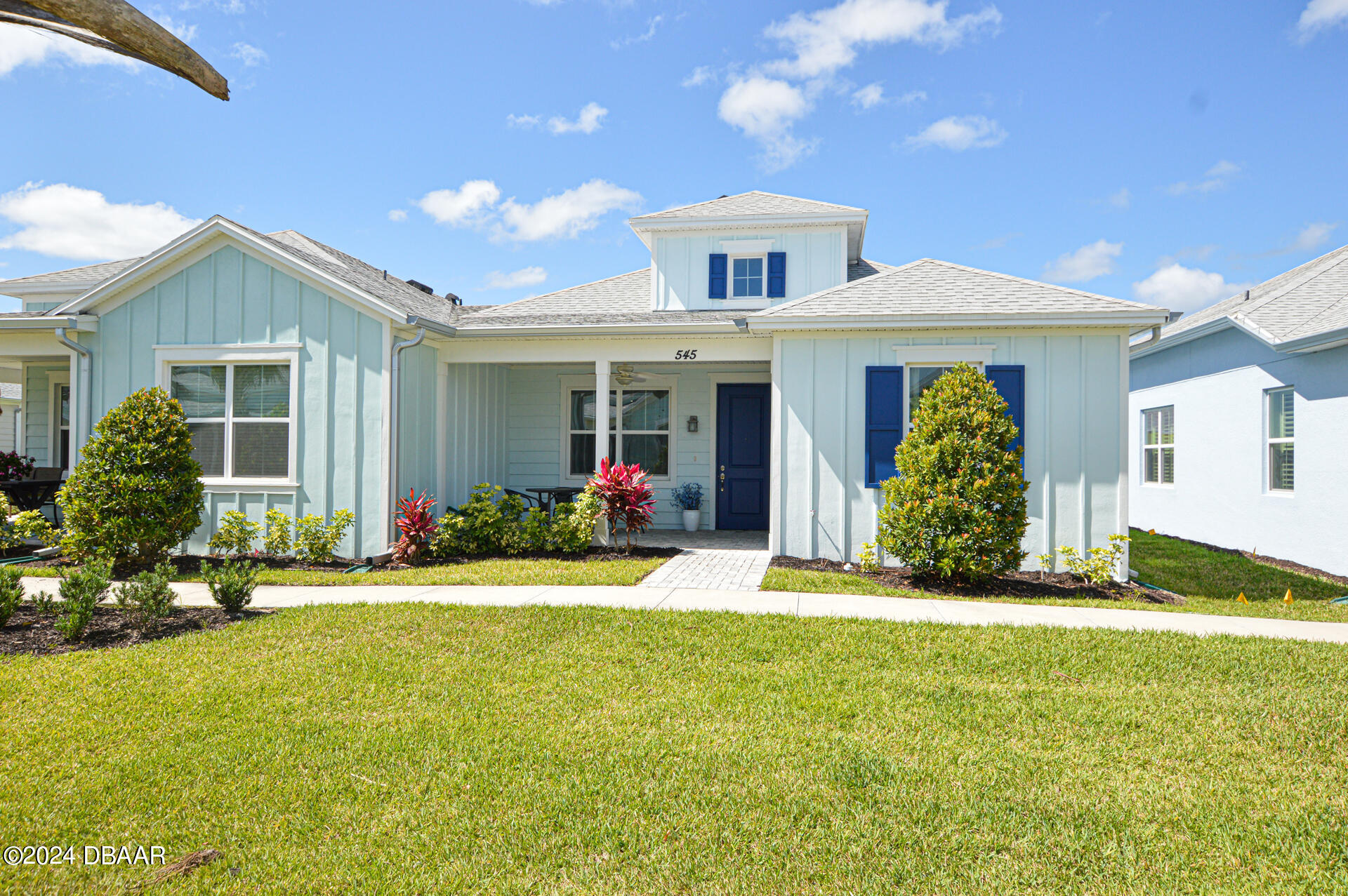 a front view of a house with a yard and potted plants