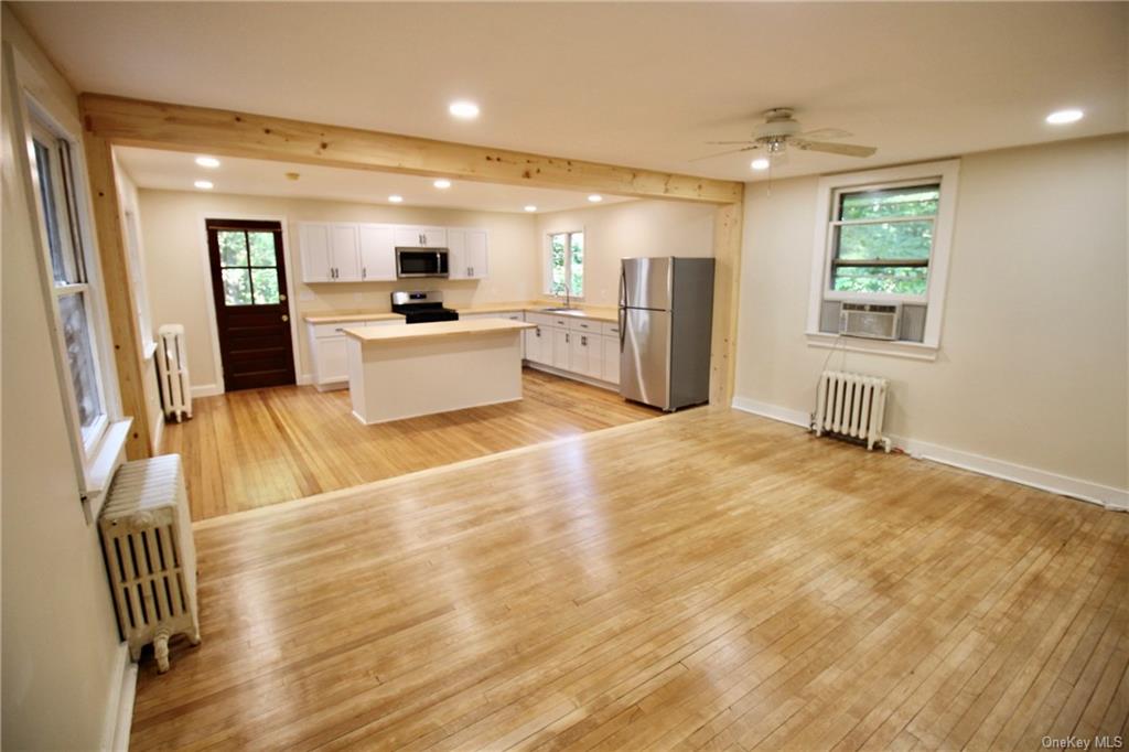 a view of a kitchen with kitchen island wooden floor and stainless steel appliances