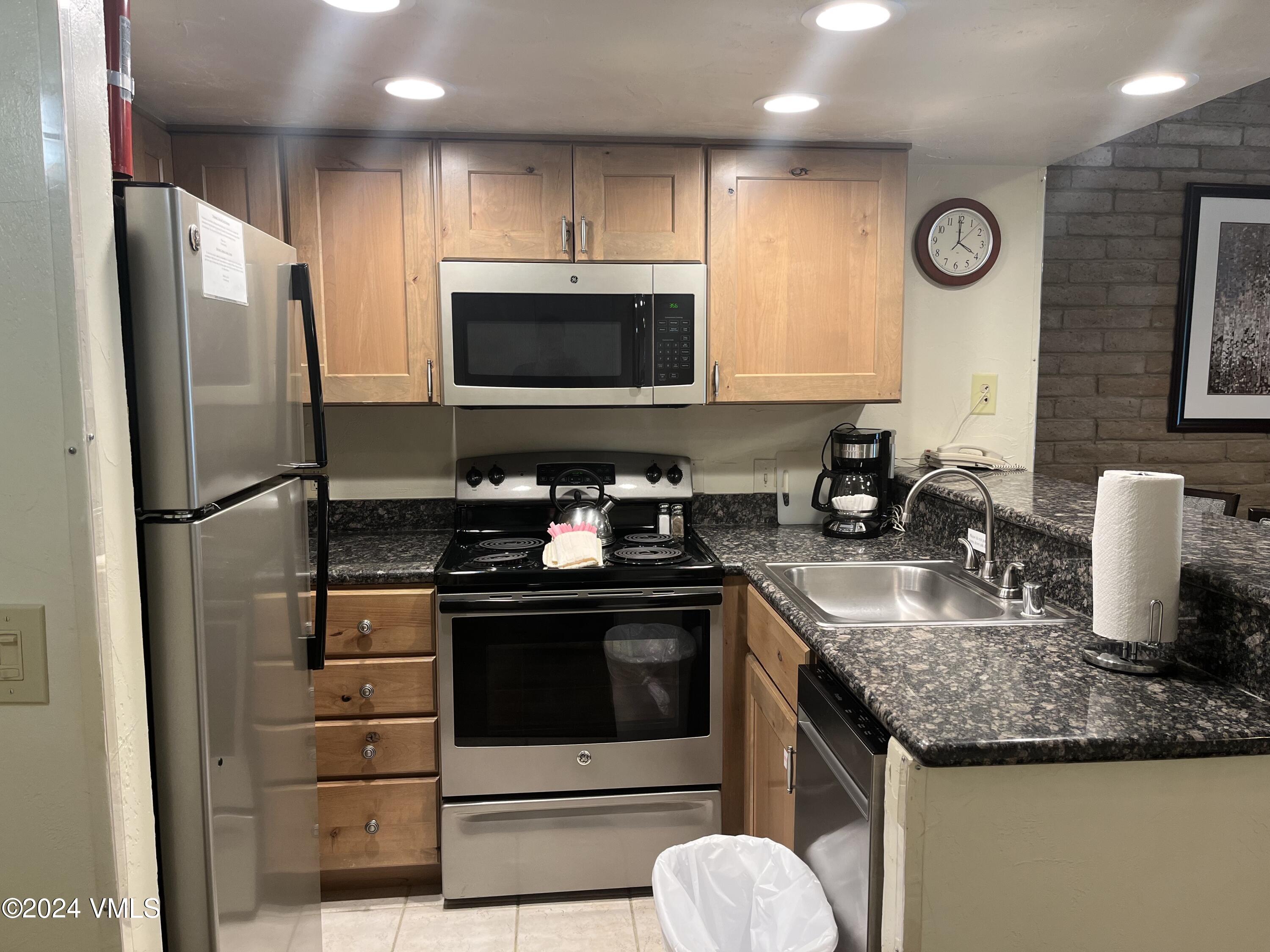 a kitchen with granite countertop a sink stove and refrigerator