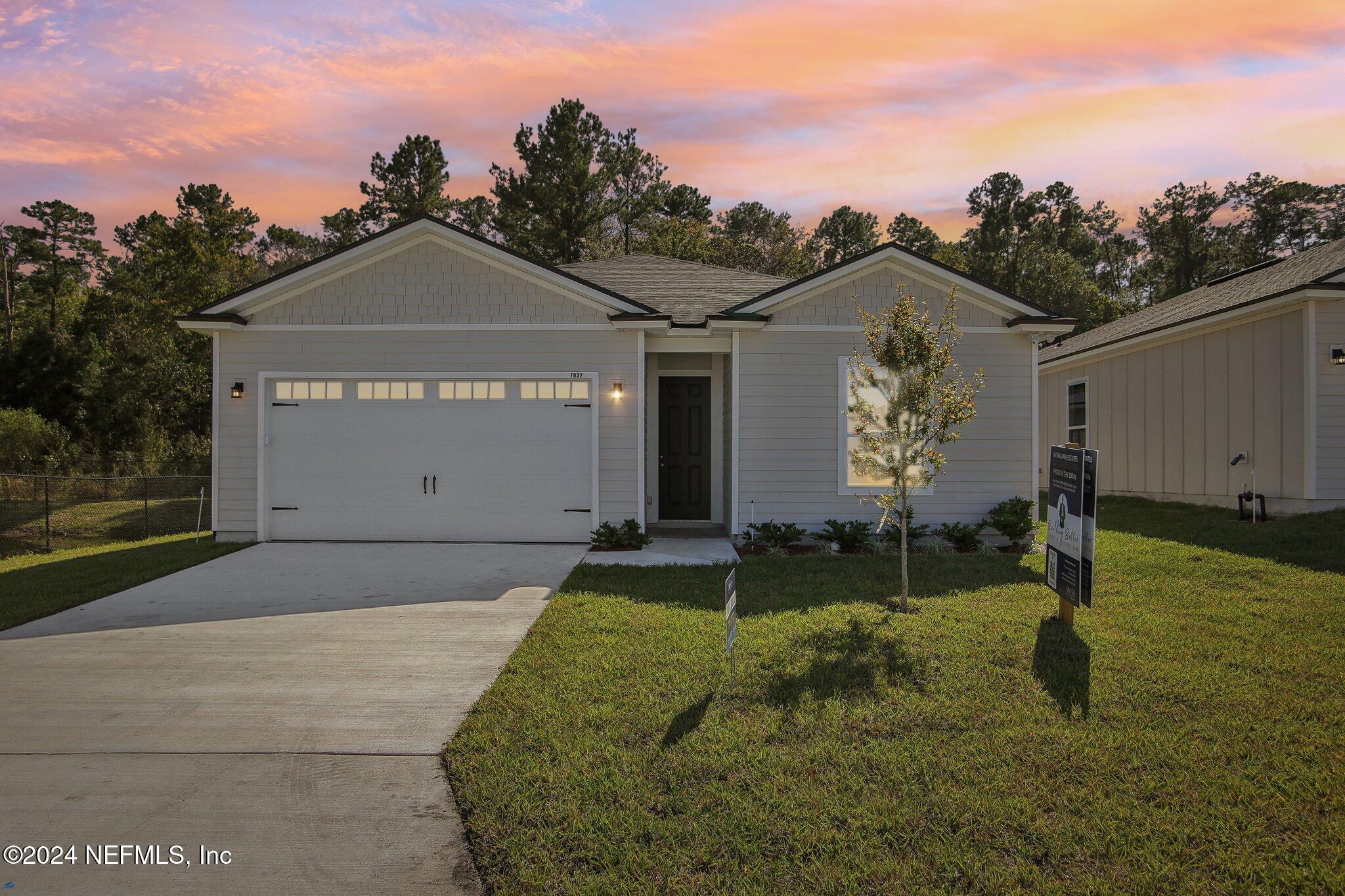 a front view of house with yard and trees in the background