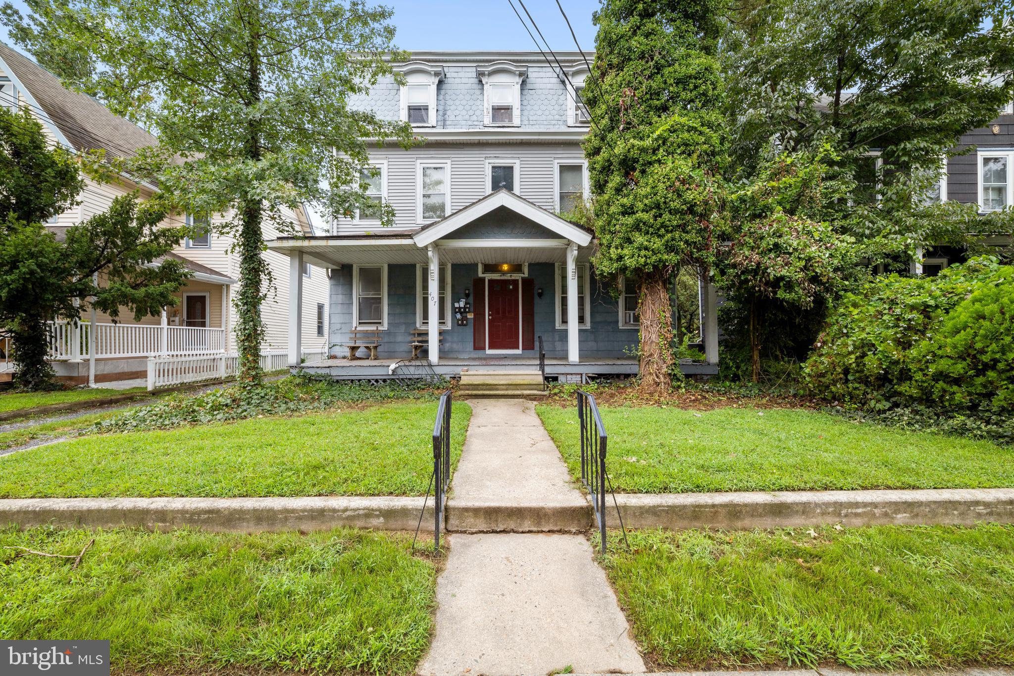 a view of a house with a yard plants and large tree