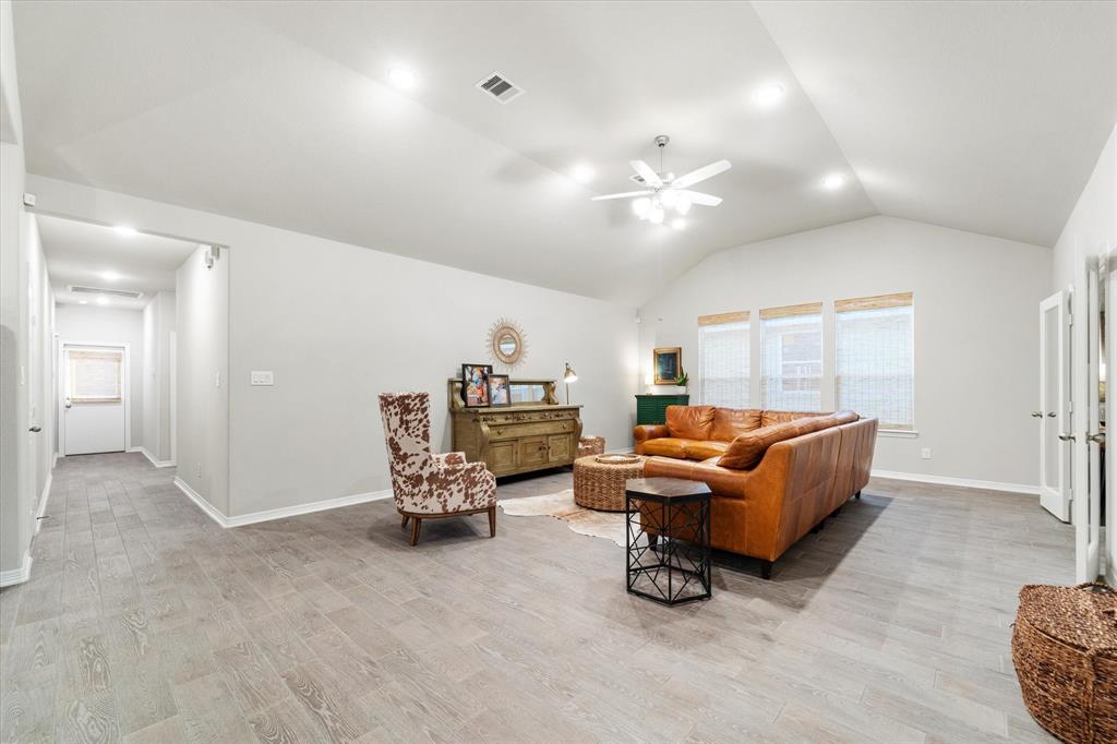 Welcome Home! As you enter, you'll be greeted by the spacious living room, featuring stylish wood-look tile flooring. The room also boasts an 11-foot ceiling with a ceiling fan, recessed lighting, and bamboo shades for a touch of privacy & style.