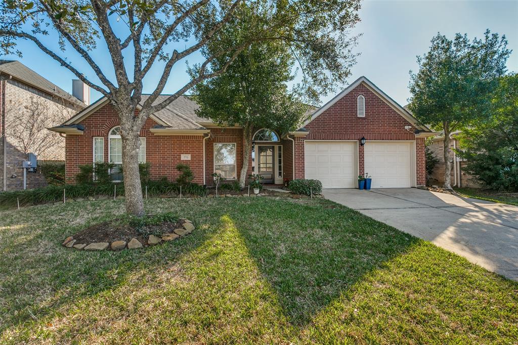 Charming brick home with a well-maintained lawn and mature trees. Features a two-car garage and a welcoming front entrance. Ideal for family living.