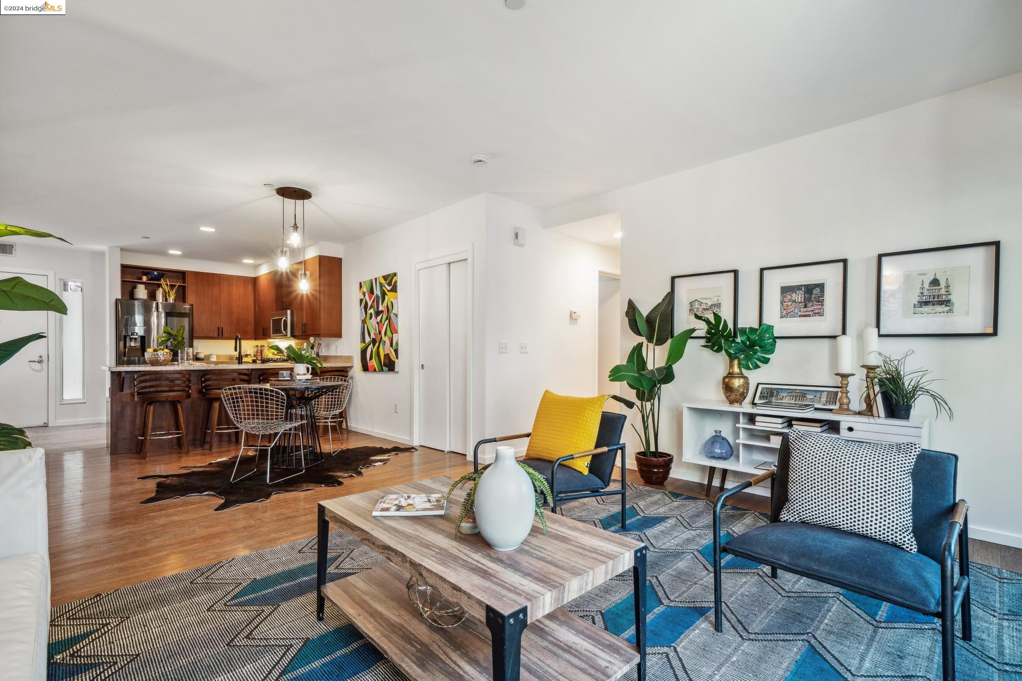 a living room with furniture kitchen view and a wooden floor