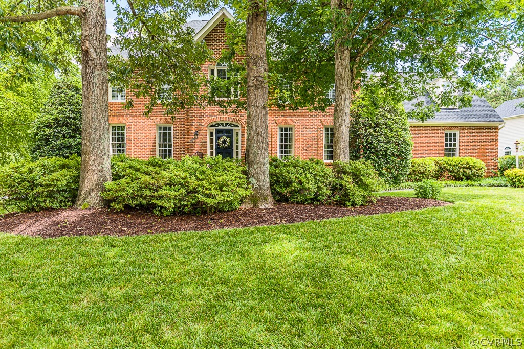 a view of a yard in front of a house with plants and large trees