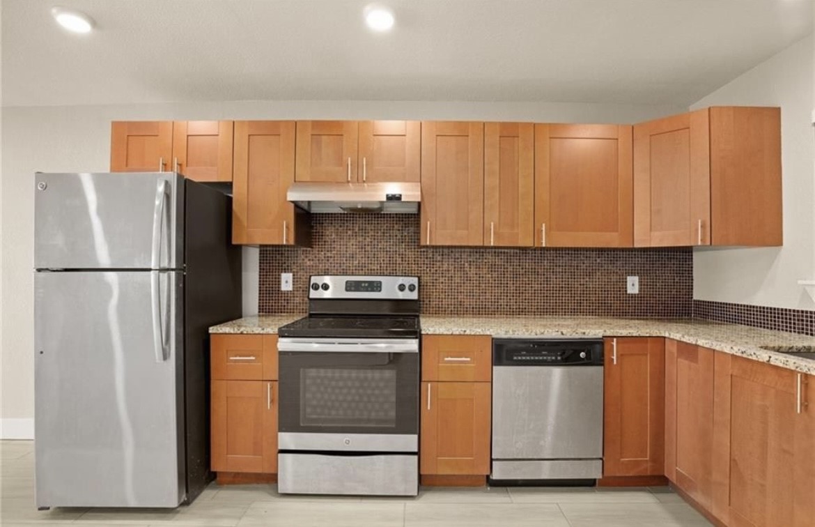 a kitchen with stainless steel appliances granite countertop a refrigerator a stove a sink and a microwave