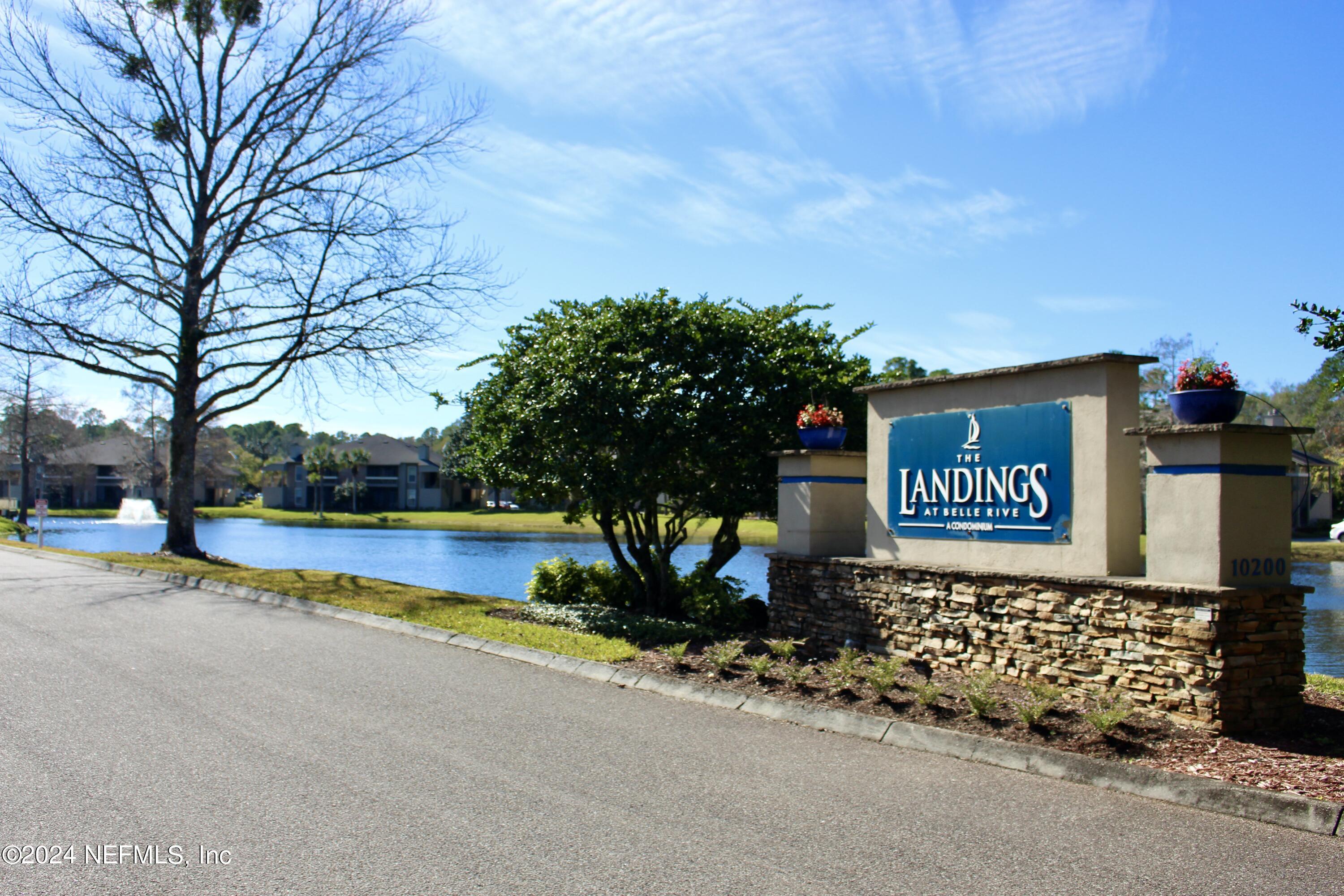 a sign board with a house and yard in the back