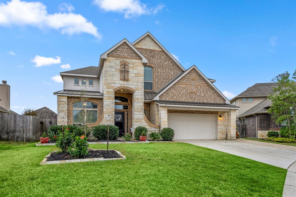 Welcome to 18123 Dorman Draw Ln – This stunning home boasts a brick and stone elevation, nestled at the edge of a quiet cul-de-sac. The well-maintained landscaping adds to its inviting curb appeal.