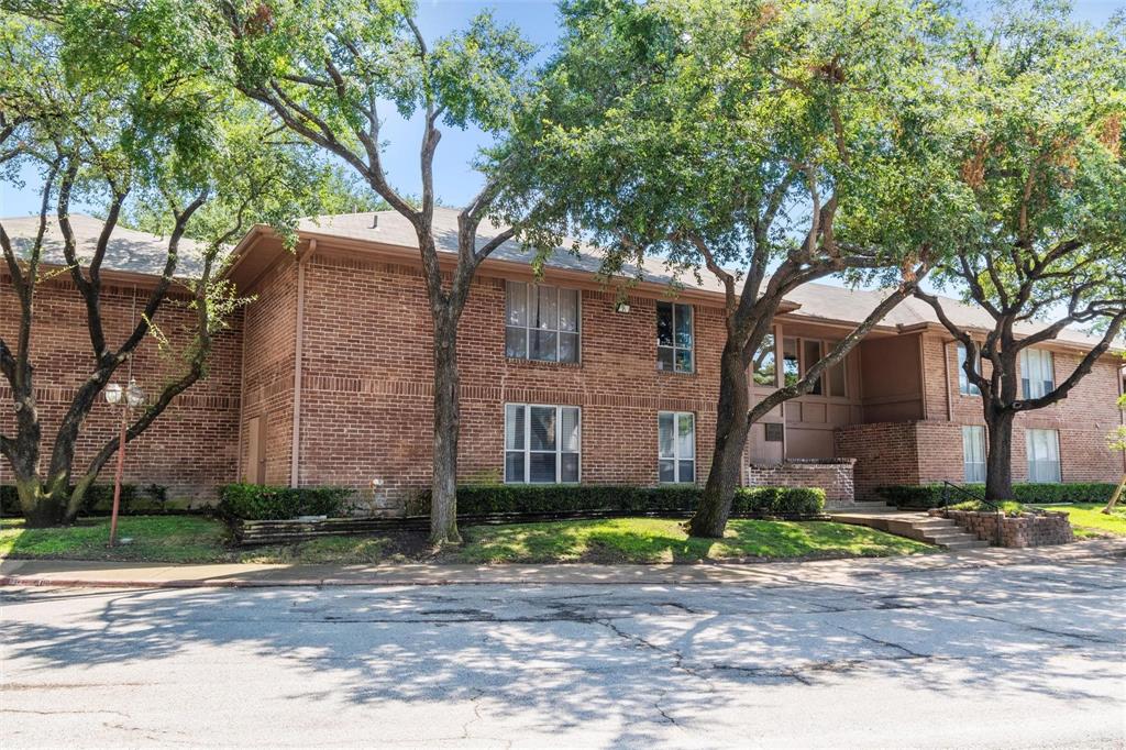 a large tree in front of a brick house