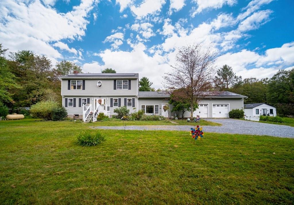 Colonial inspired home with a garage and a front yard