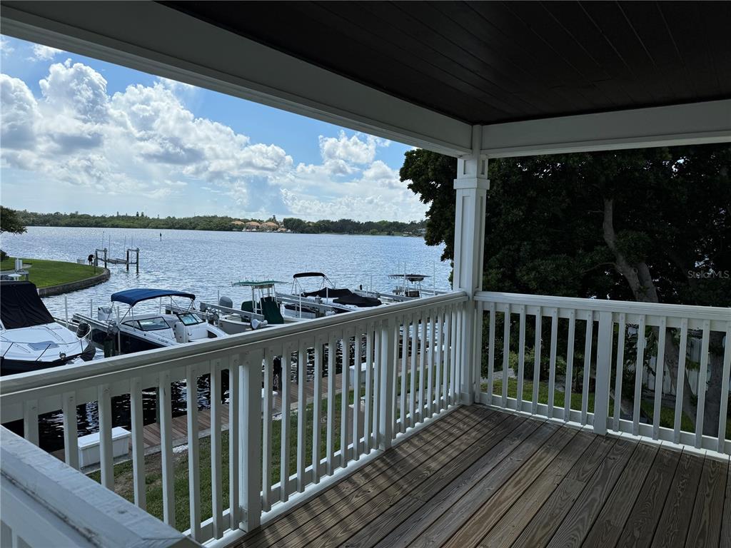 a balcony with wooden floor outdoor seating and yard in the back