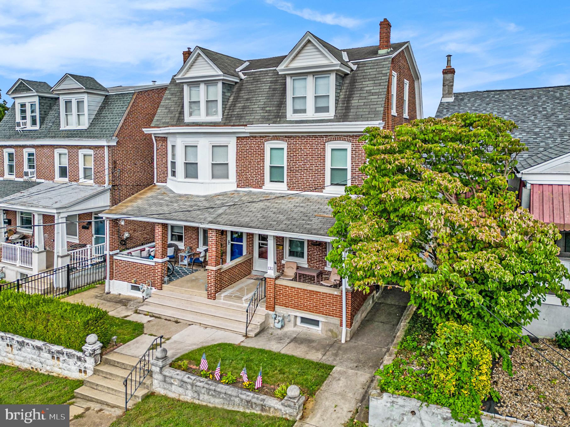 front view of a brick house with a yard and plants