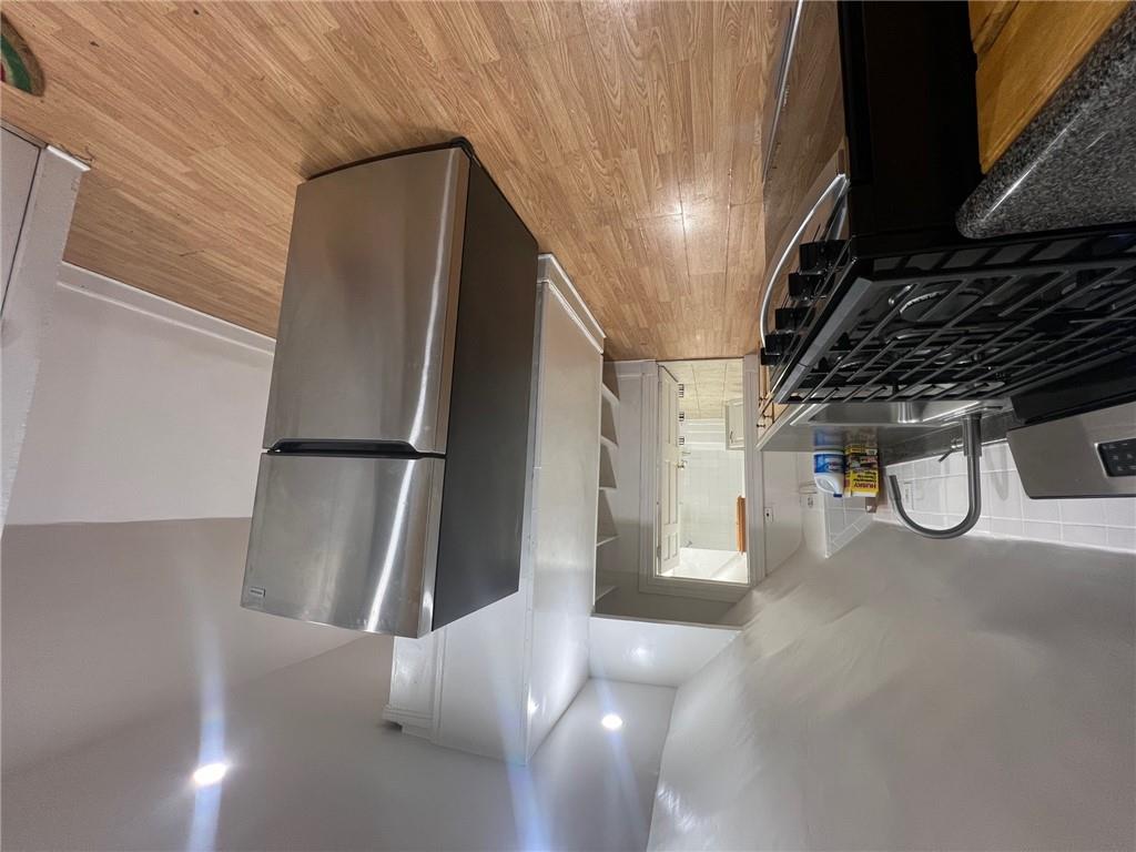 Kitchen with sink, fridge, stainless steel range, light wood-type flooring, and vaulted ceiling