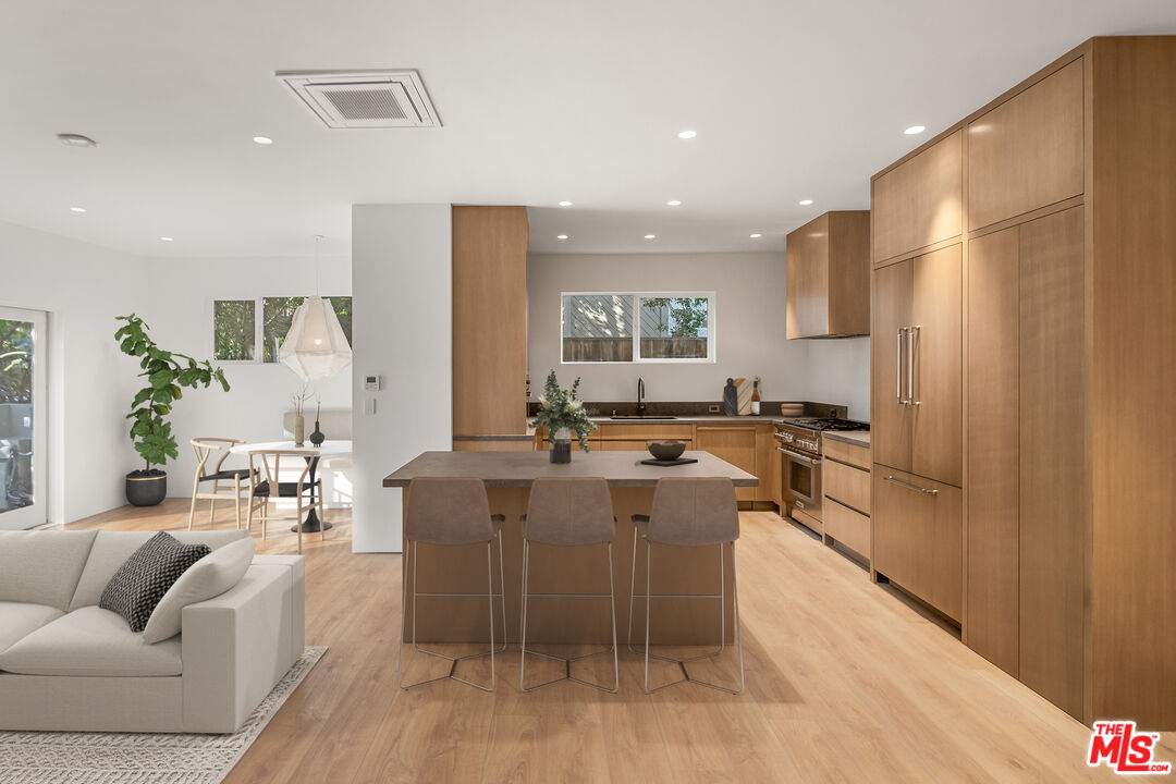 a living room with stainless steel appliances furniture a rug and a kitchen view