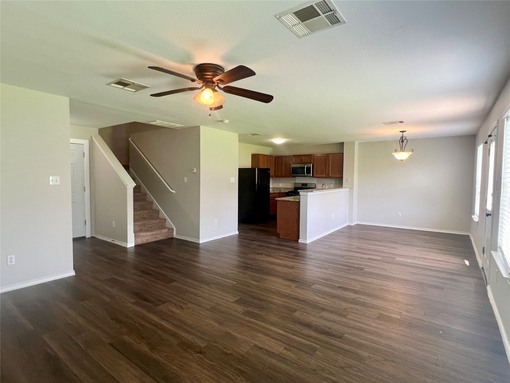 a view of an empty room with wooden floor and a ceiling fan