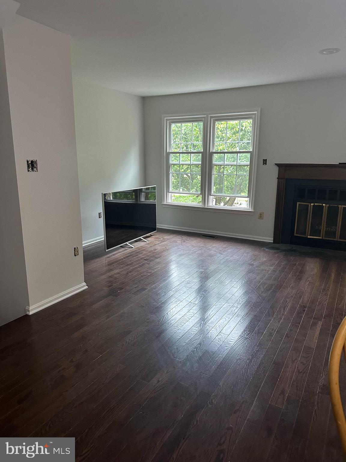 an empty room with wooden floor fireplace and windows