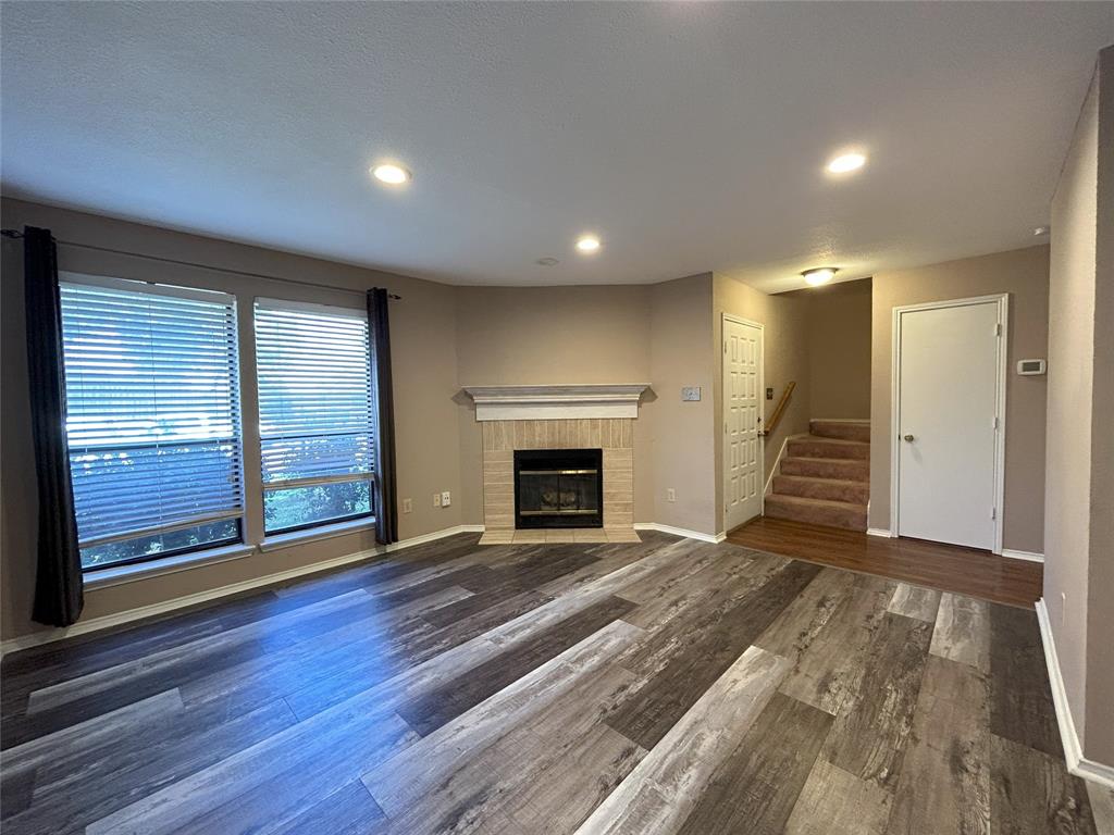 an empty room with wooden floor fireplace and windows