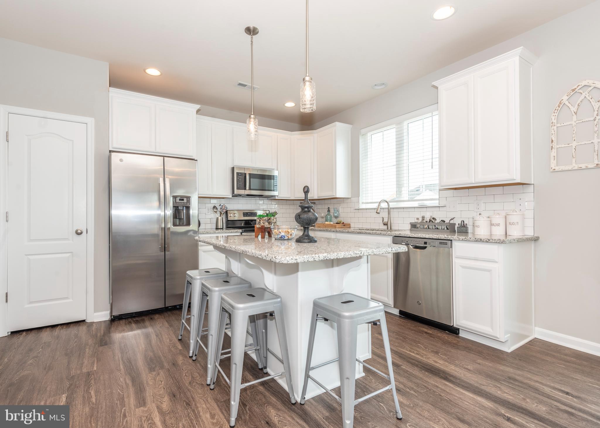 a kitchen with kitchen island granite countertop a center island stainless steel appliances cabinets and a window