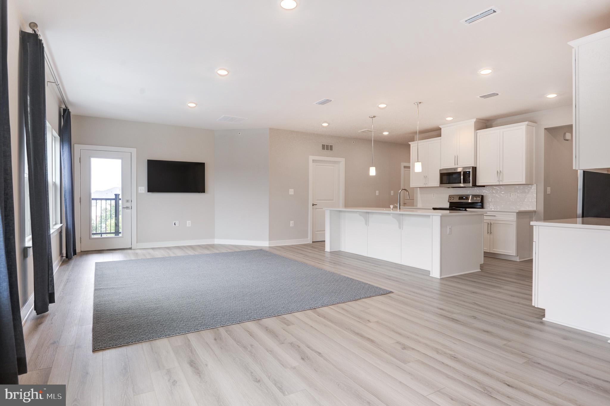 a view of kitchen with kitchen island granite countertop a stove top oven a sink and white cabinets with wooden floor