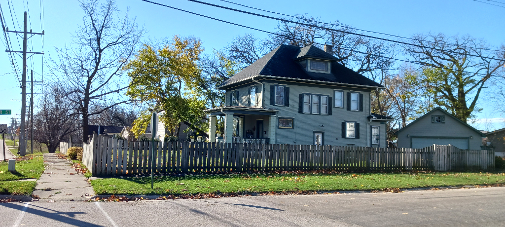 a view of a brick house with a small yard plants and large trees