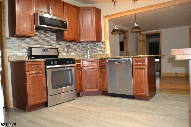 a kitchen with stainless steel appliances granite countertop a stove a sink and a microwave