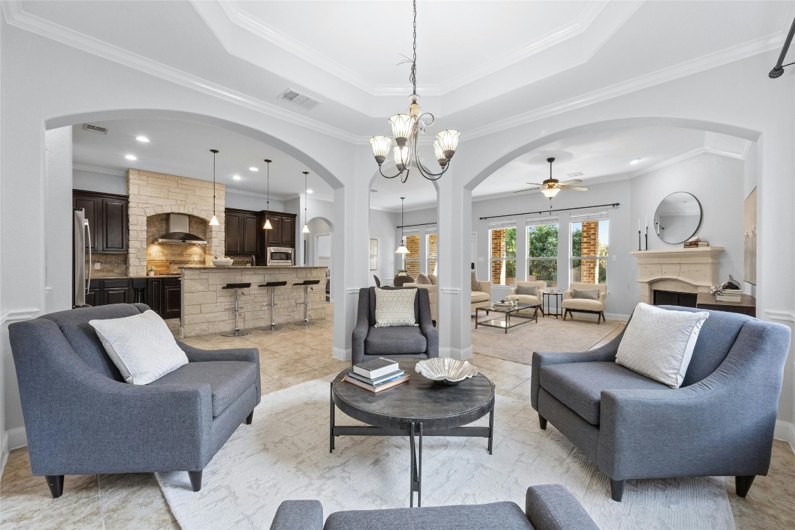 a living room with furniture kitchen view and a chandelier