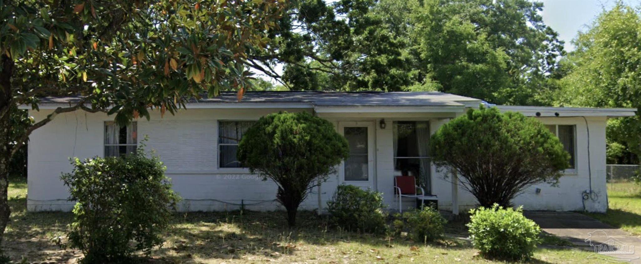 a view of a house with potted plants and large trees