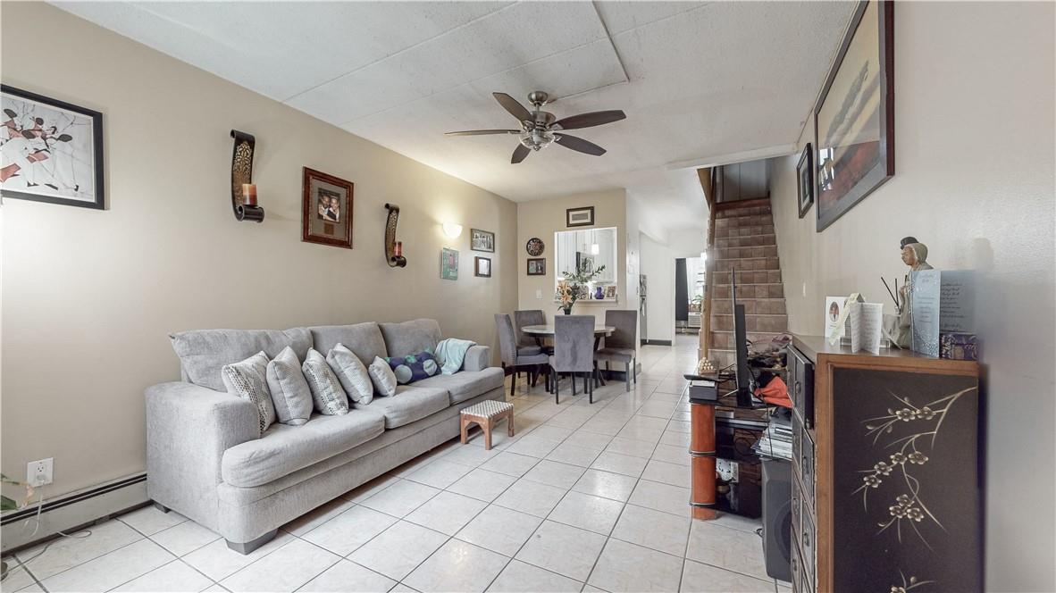 Living room featuring a baseboard radiator, ceiling fan, and light tile patterned flooring