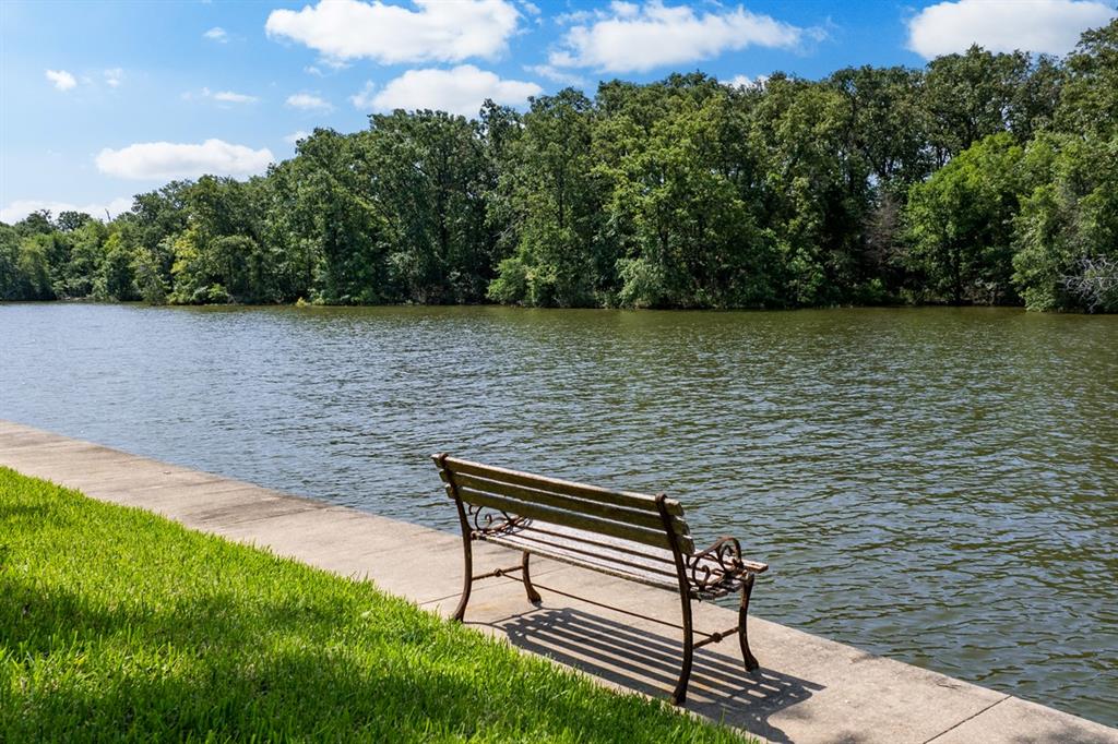 a lake view with a bench and trees in the background