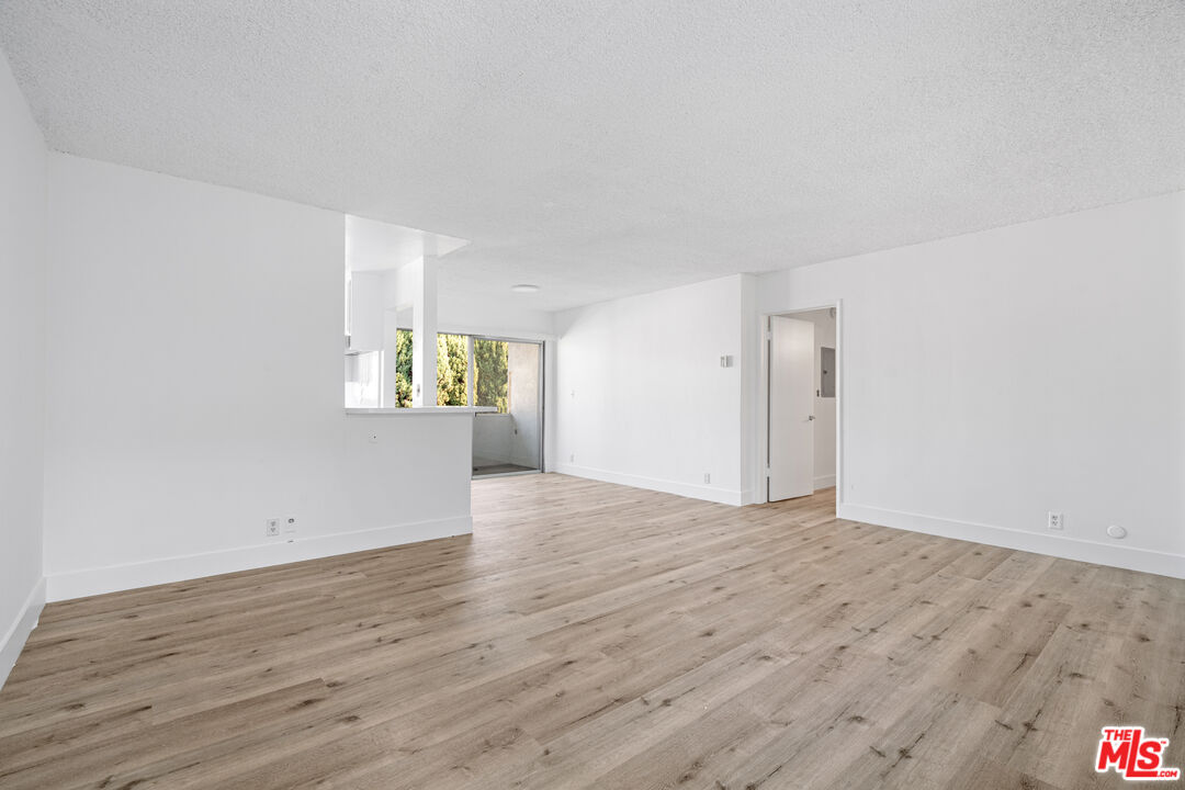 a view of an empty room with window and wooden floor