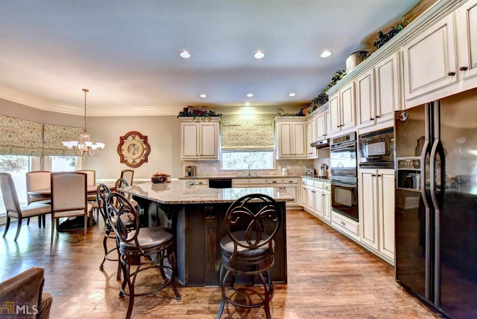 a kitchen with stainless steel appliances a dining table chairs stove refrigerator and cabinets