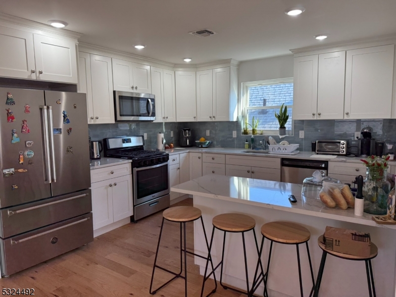 a kitchen with stainless steel appliances kitchen island granite countertop a refrigerator and microwave