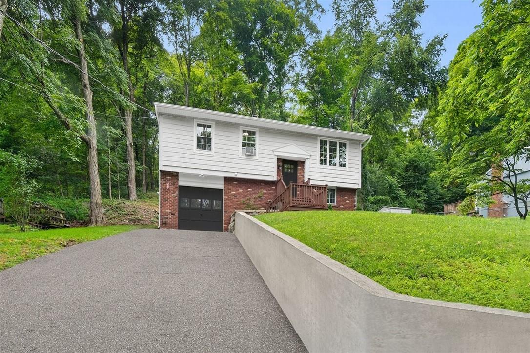 Split foyer home featuring a garage and a front lawn