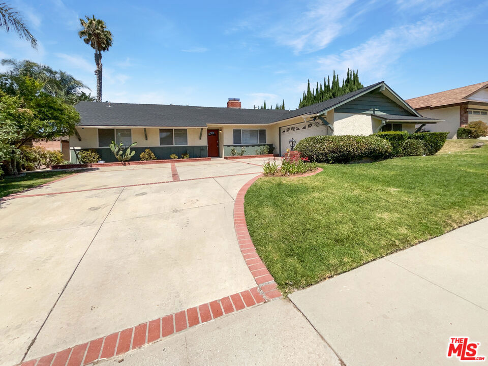 a front view of a house with a yard and potted plants