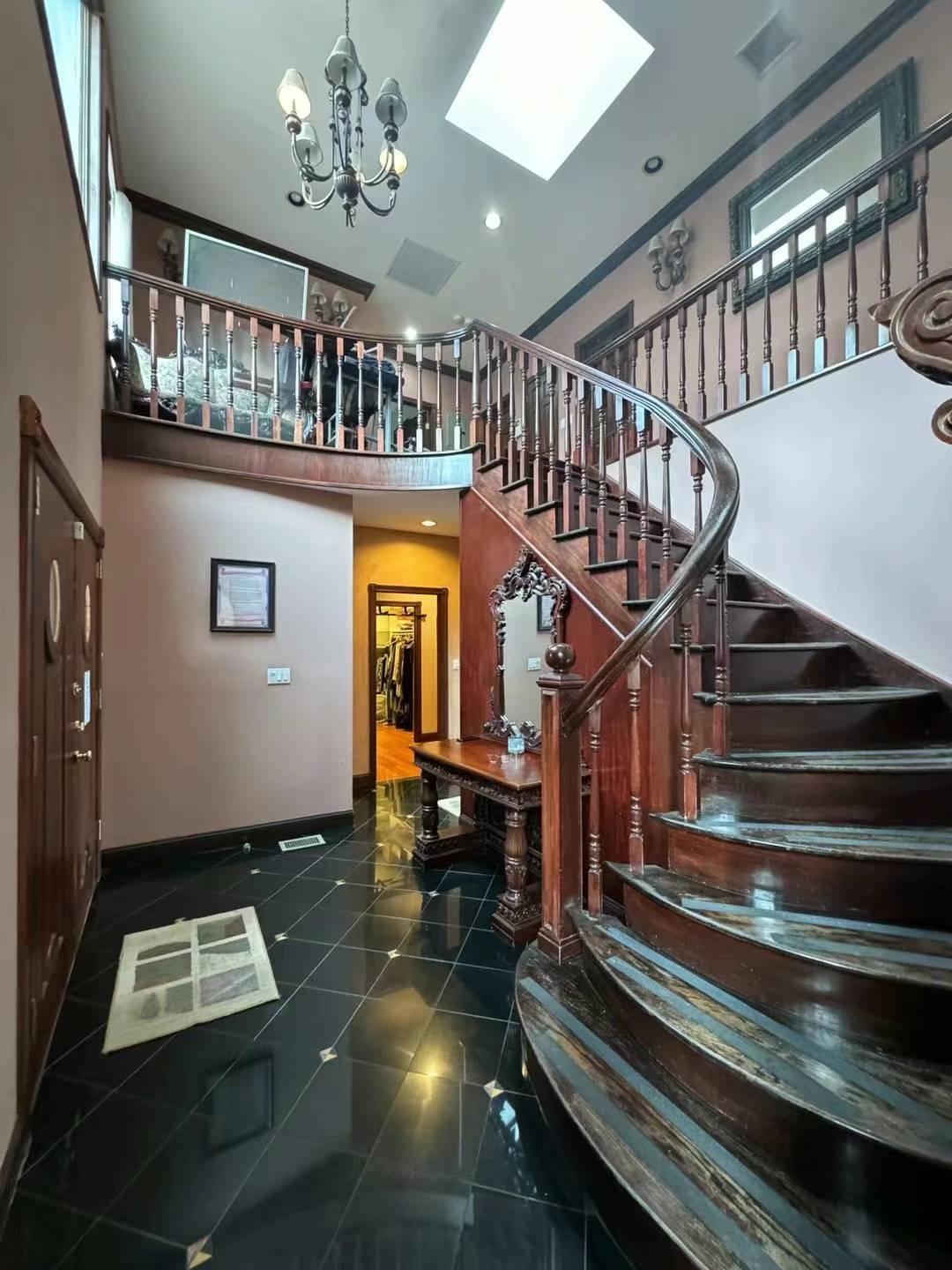 Stairs with a skylight, a high ceiling, and a chandelier