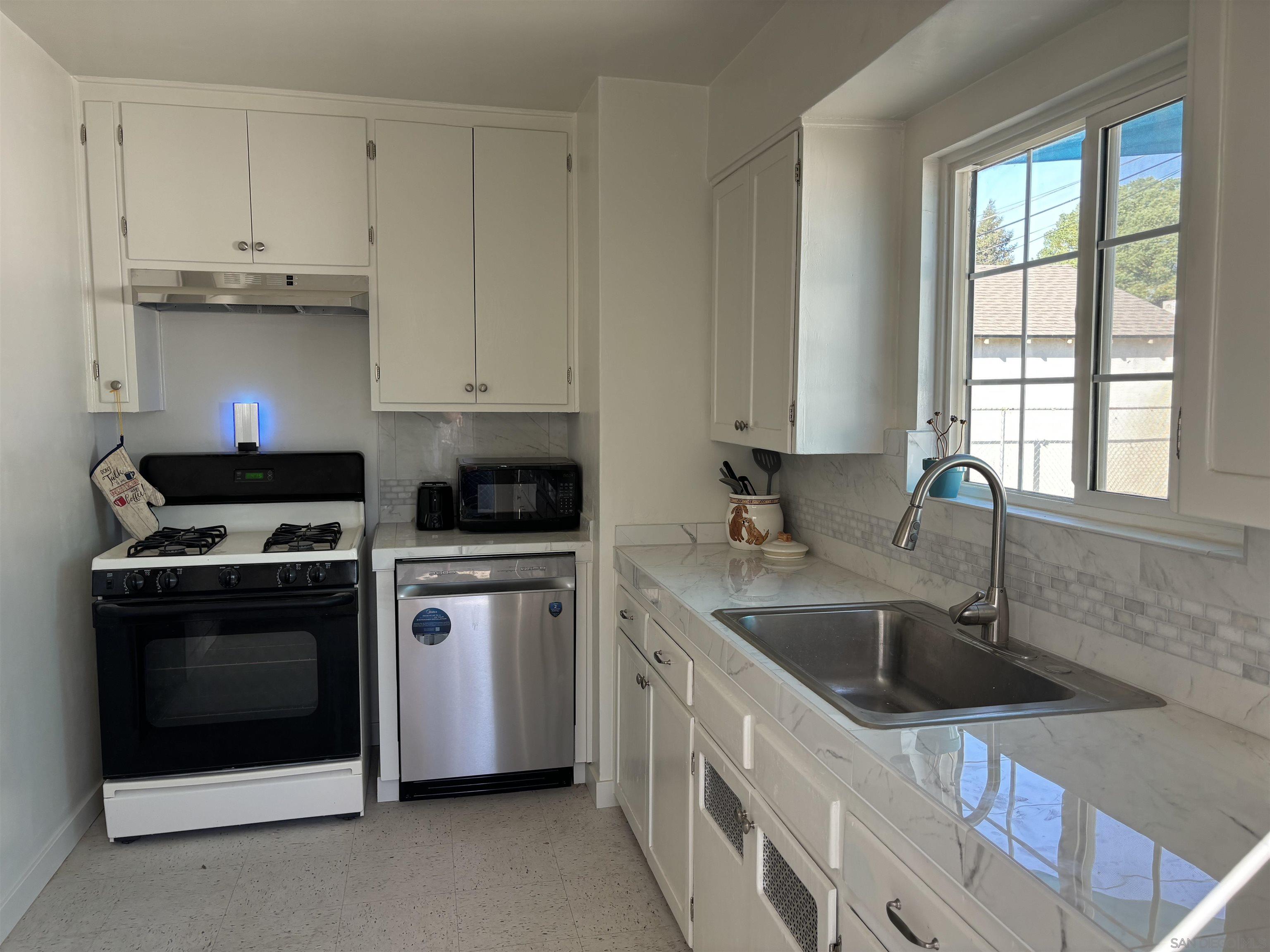 a kitchen with stainless steel appliances granite countertop a sink stove and white cabinets