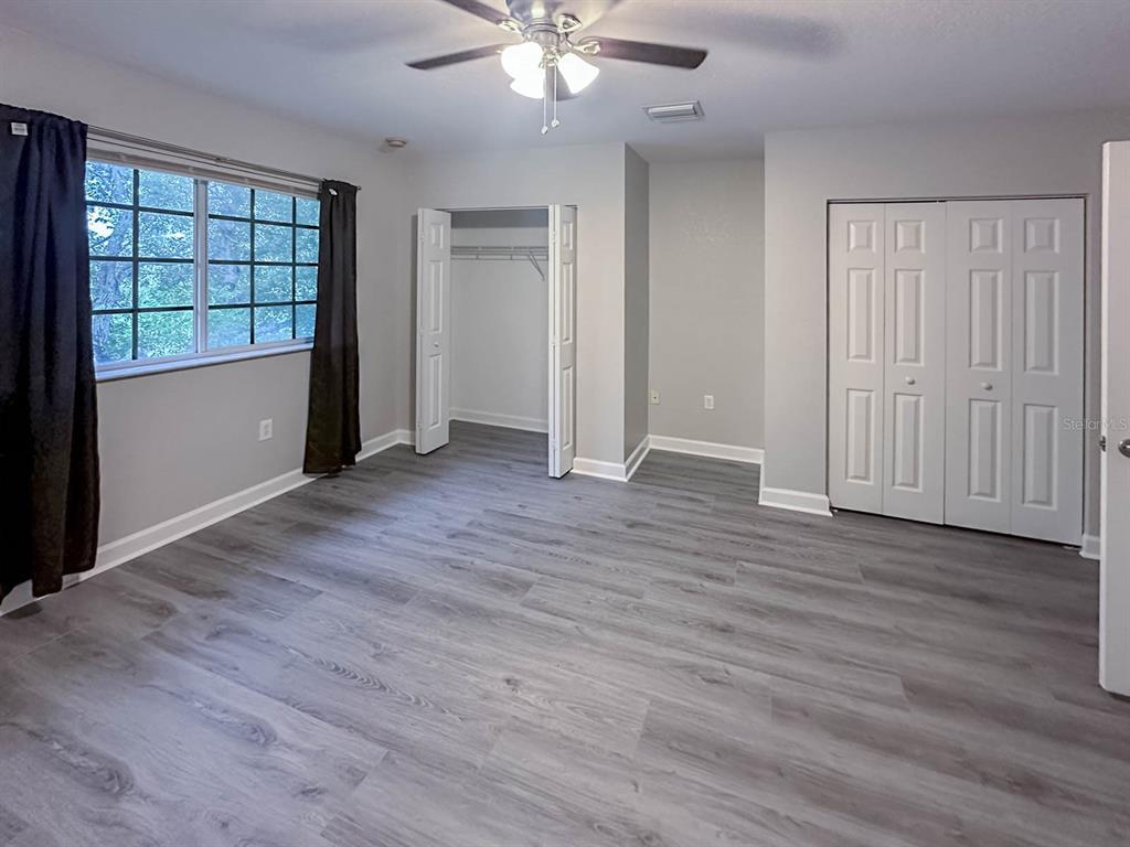 an empty room with wooden floor cabinet and windows