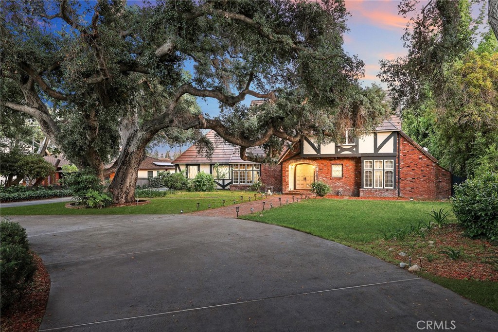 a view of a house with a yard and large trees