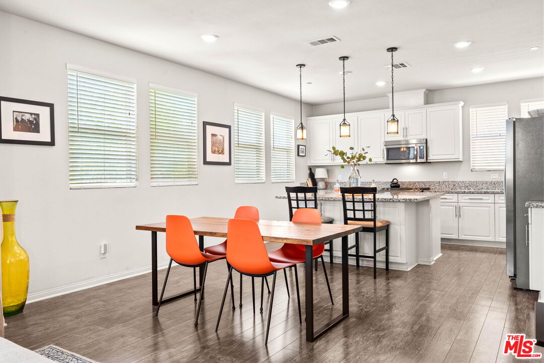 a kitchen with stainless steel appliances kitchen island granite countertop a table chairs sink and cabinets