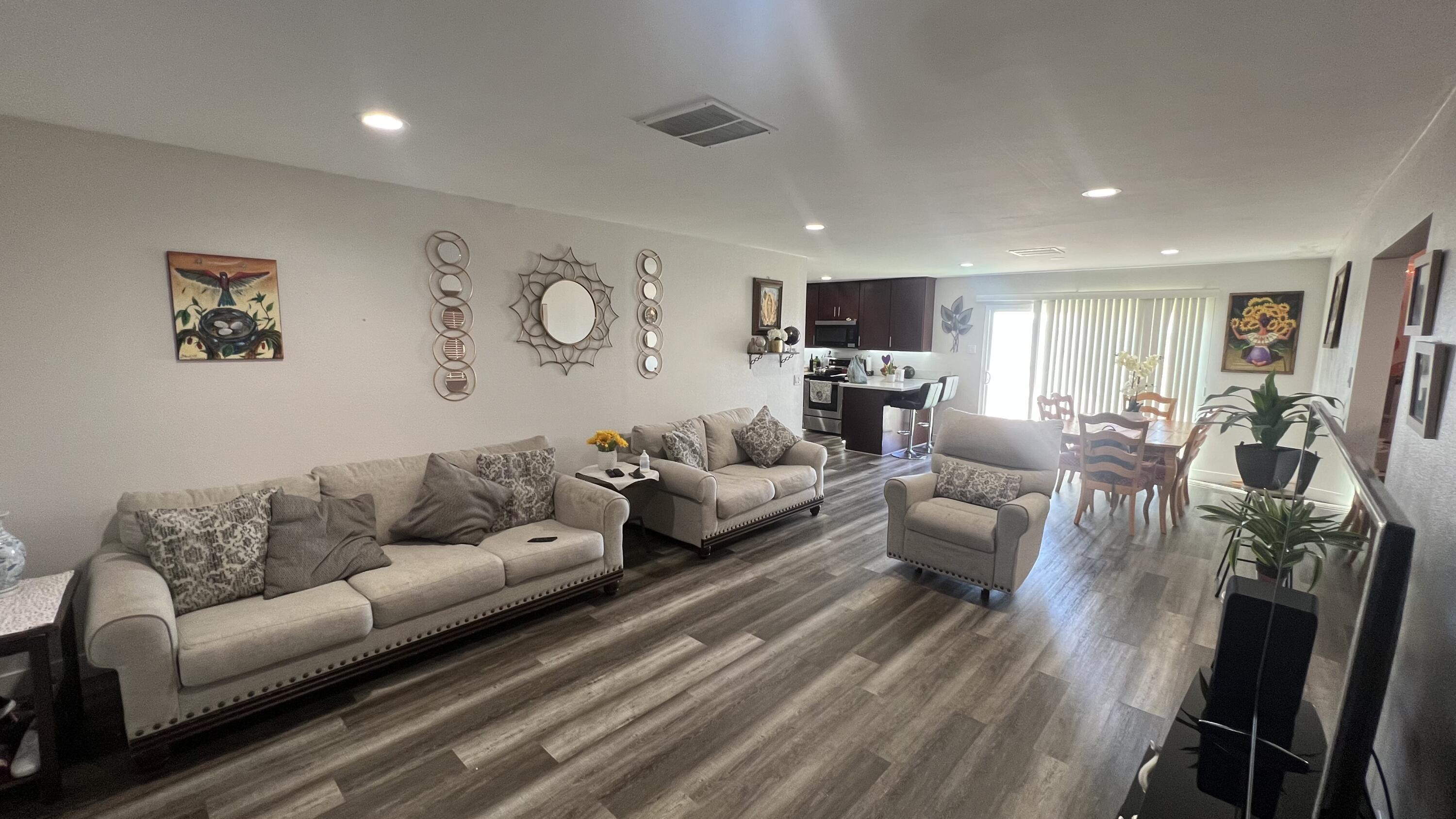 a living room with furniture kitchen view and a wooden floor