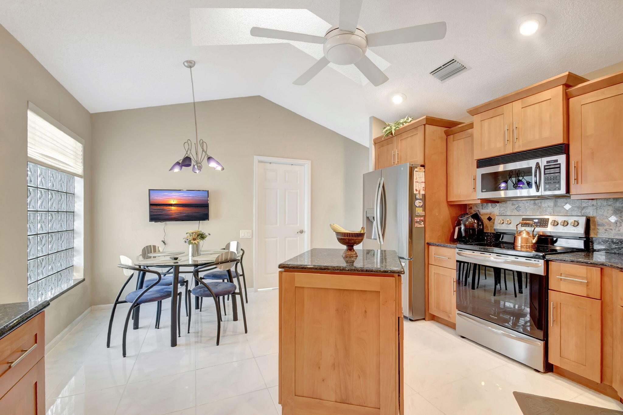 a kitchen with stainless steel appliances kitchen island granite countertop a stove top oven a sink a dining table and chairs with wooden floor