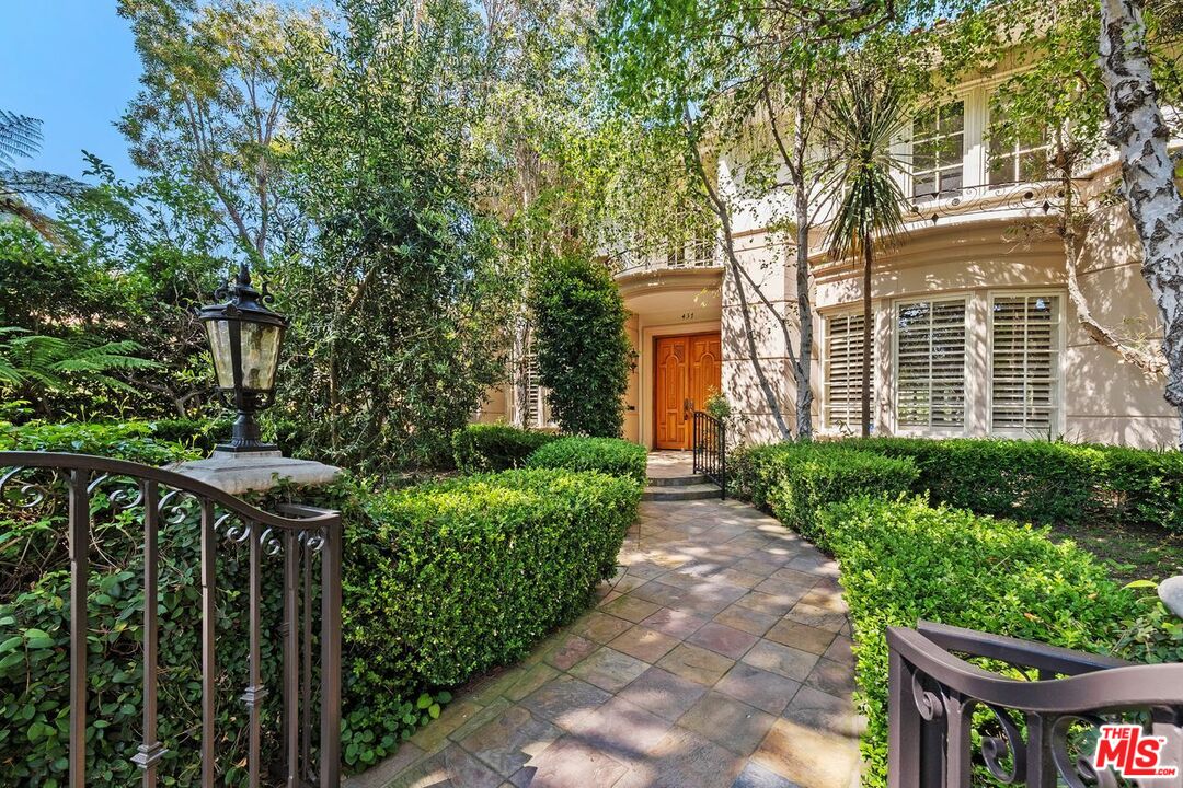 a view of a pathway of a house with plants and large trees