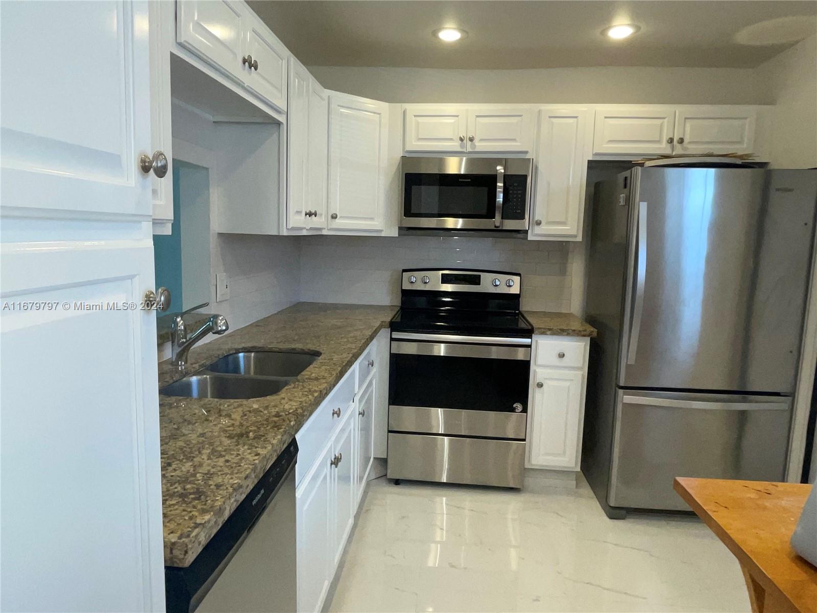 a kitchen with white cabinets stainless steel appliances and a refrigerator