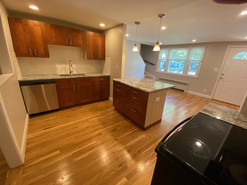 a kitchen with kitchen island granite countertop a sink and a stove top oven