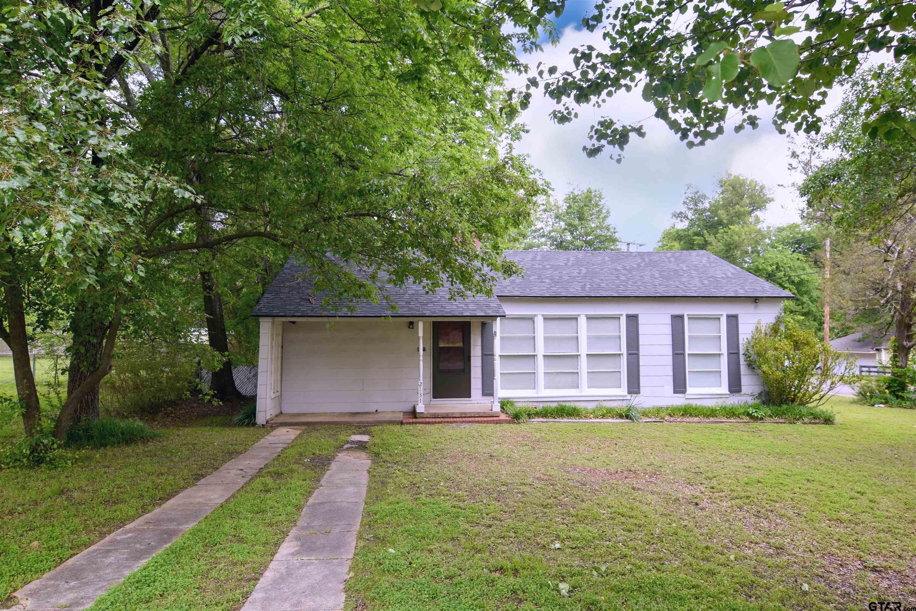 a view of a house with a yard and large tree