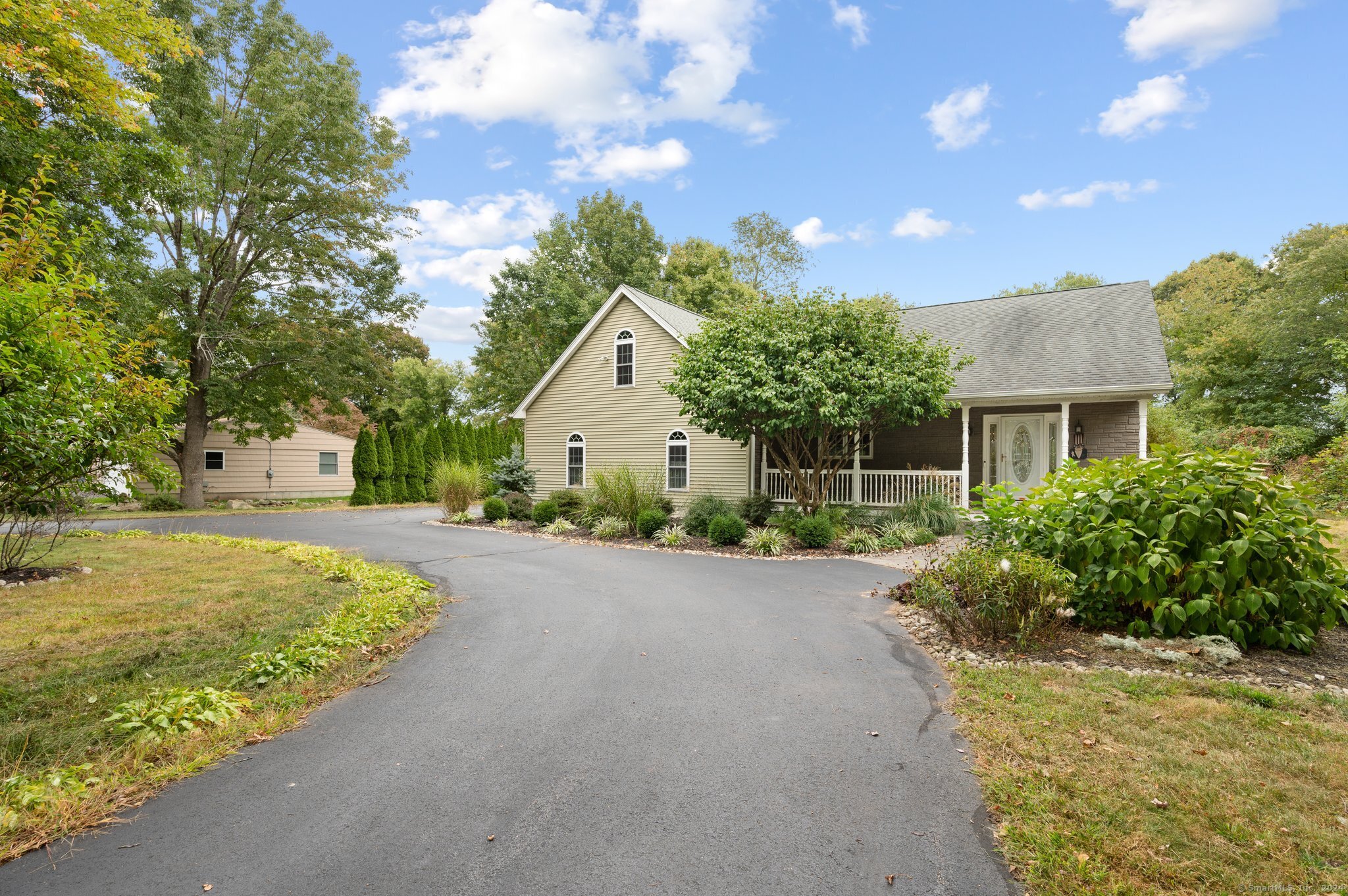 a front view of a house with a garden and trees