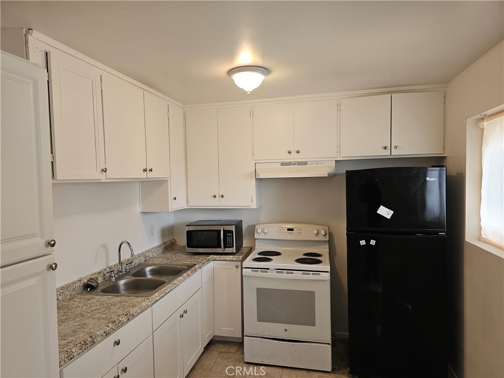 a kitchen with granite countertop white cabinets and refrigerator