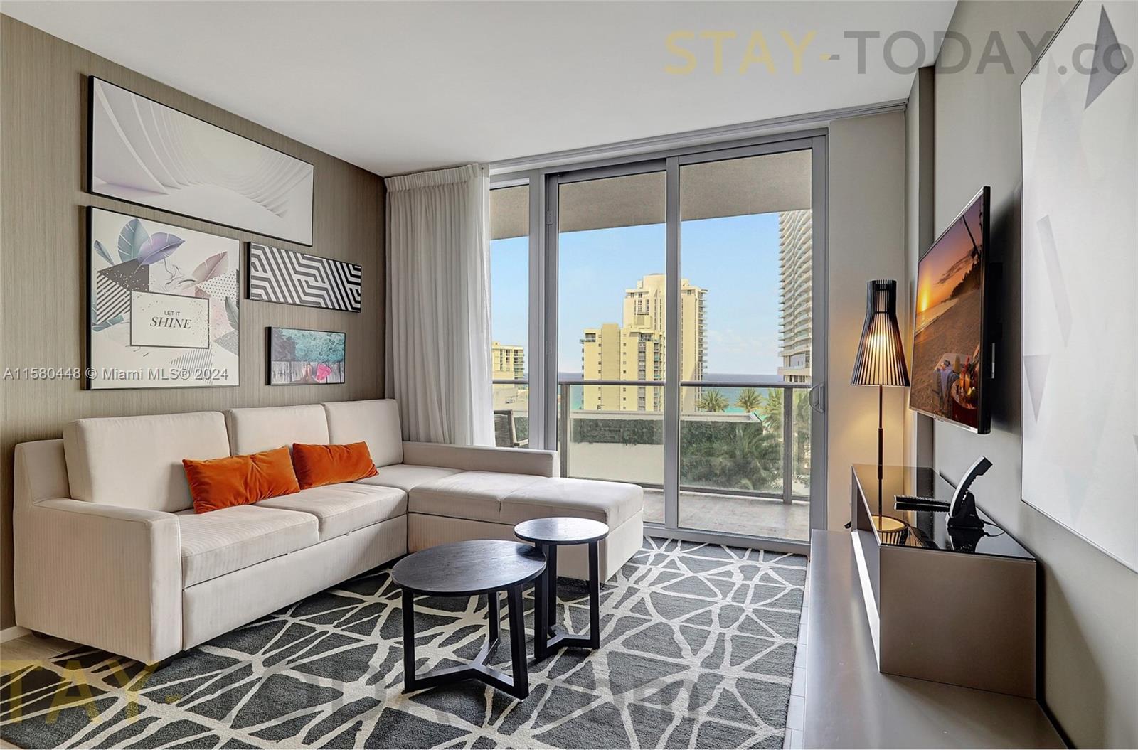 a living room with furniture a flat screen tv and a floor to ceiling window